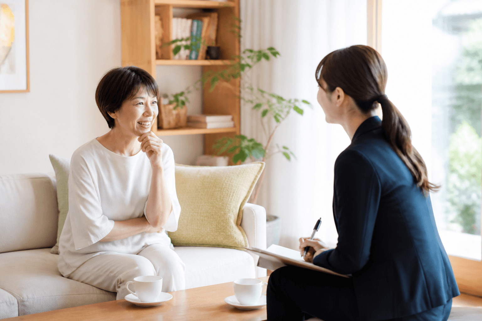 ライターがお客様のご自宅などで和やかに取材している様子の写真。リラックスした雰囲気で対話している場面。]