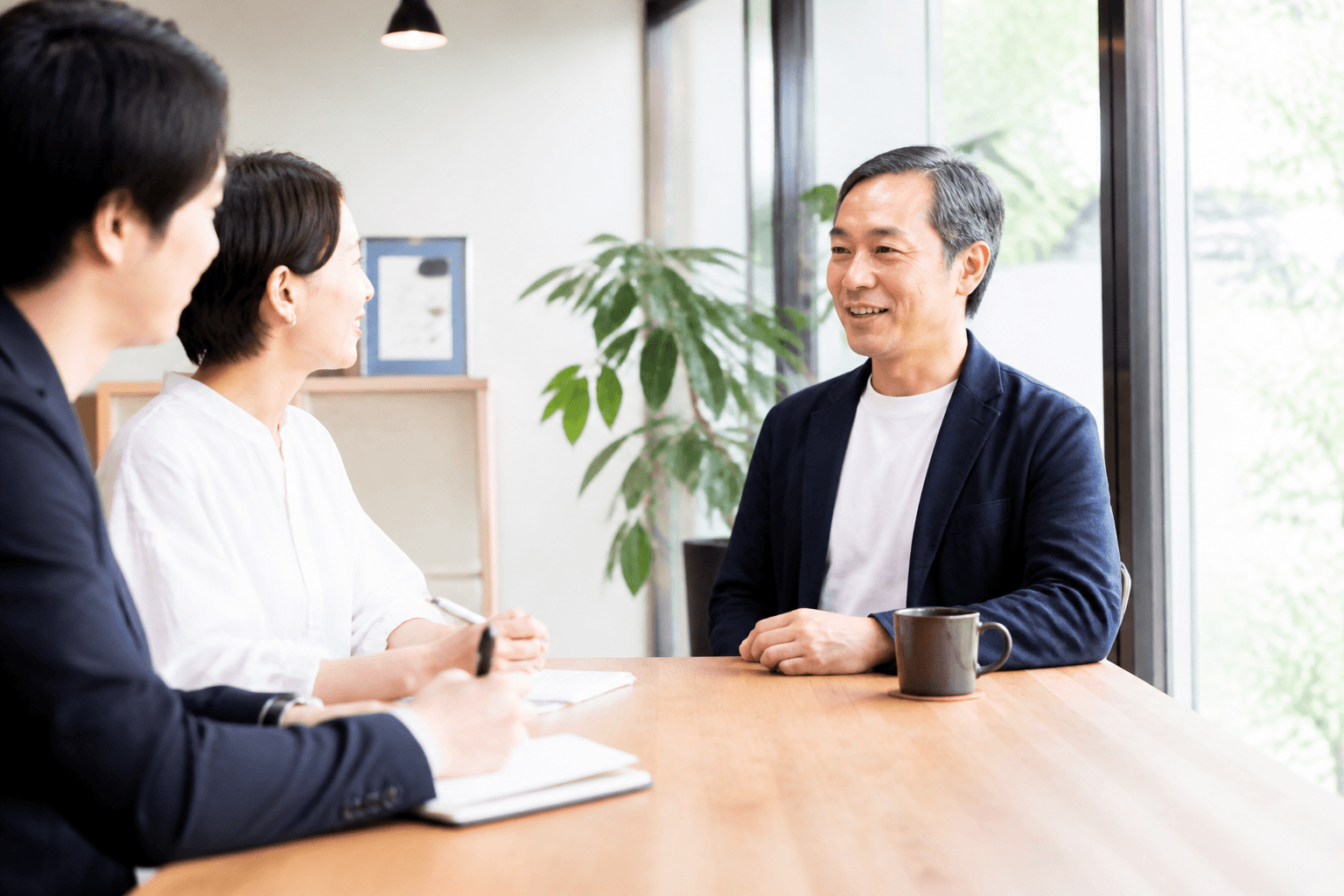 編集者とライターが、著者の方と和やかな雰囲気で取材（対話）している様子の写真。安心感と信頼感を伝える。]