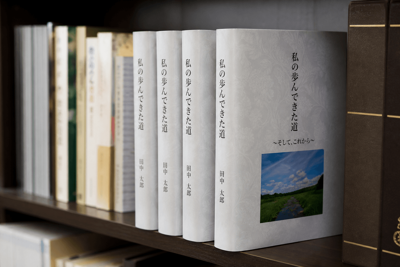完成した自分史の本が数冊、本棚に美しく並べられている写真や、家族が笑顔で本を読んでいる様子の写真。]