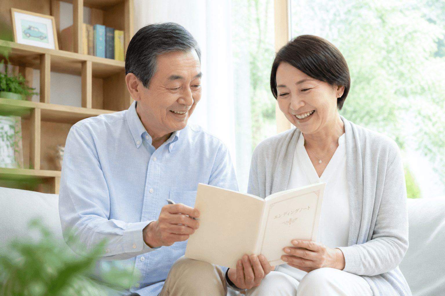 穏やかな表情でエンディングノートを見ながら談笑する60代〜70代の夫婦の写真。終活が前向きな活動であることを伝えるため。]