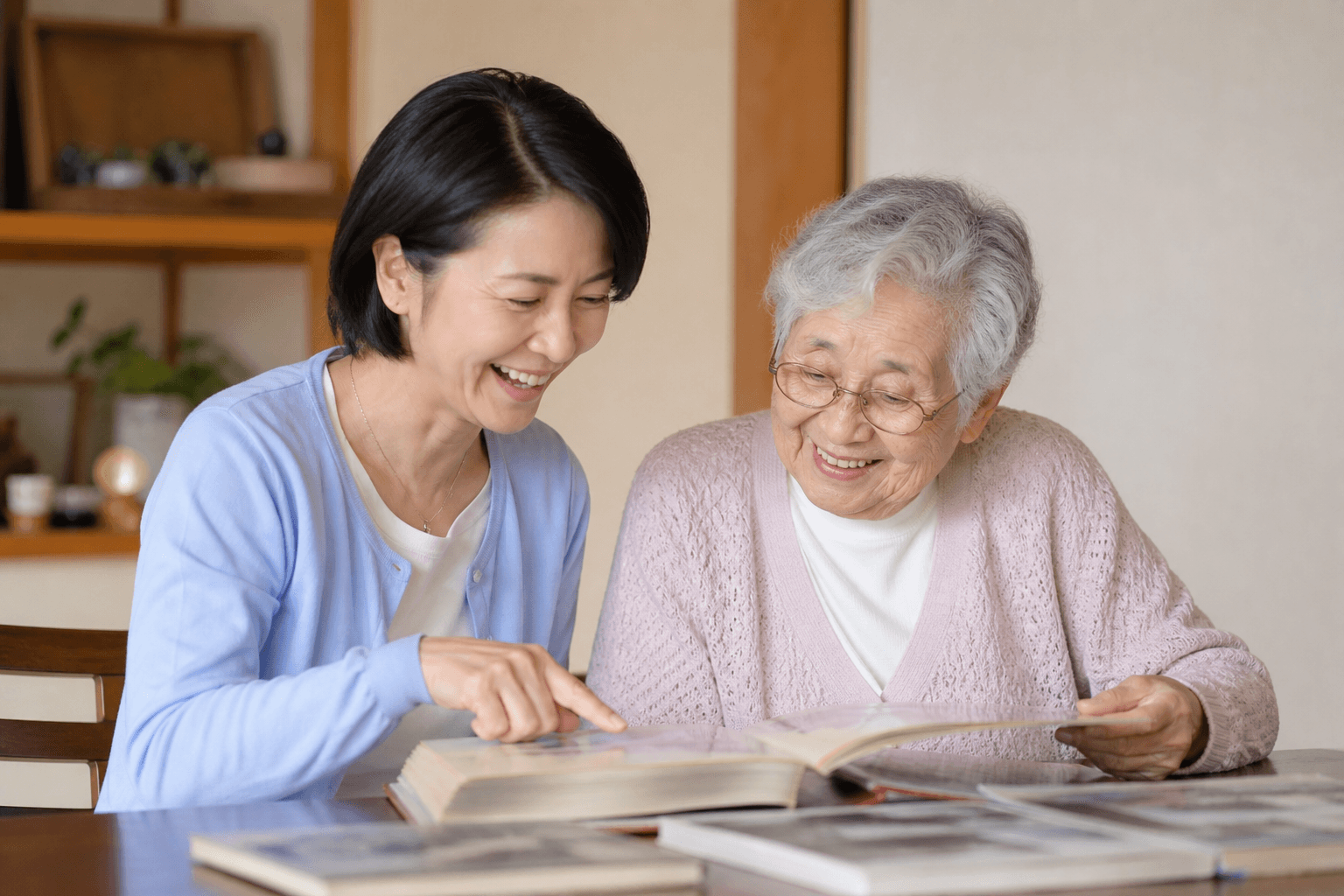 40代〜50代の子どもが、70代〜80代の親と一緒に昔のアルバムをめくりながら楽しそうに話している様子の写真]