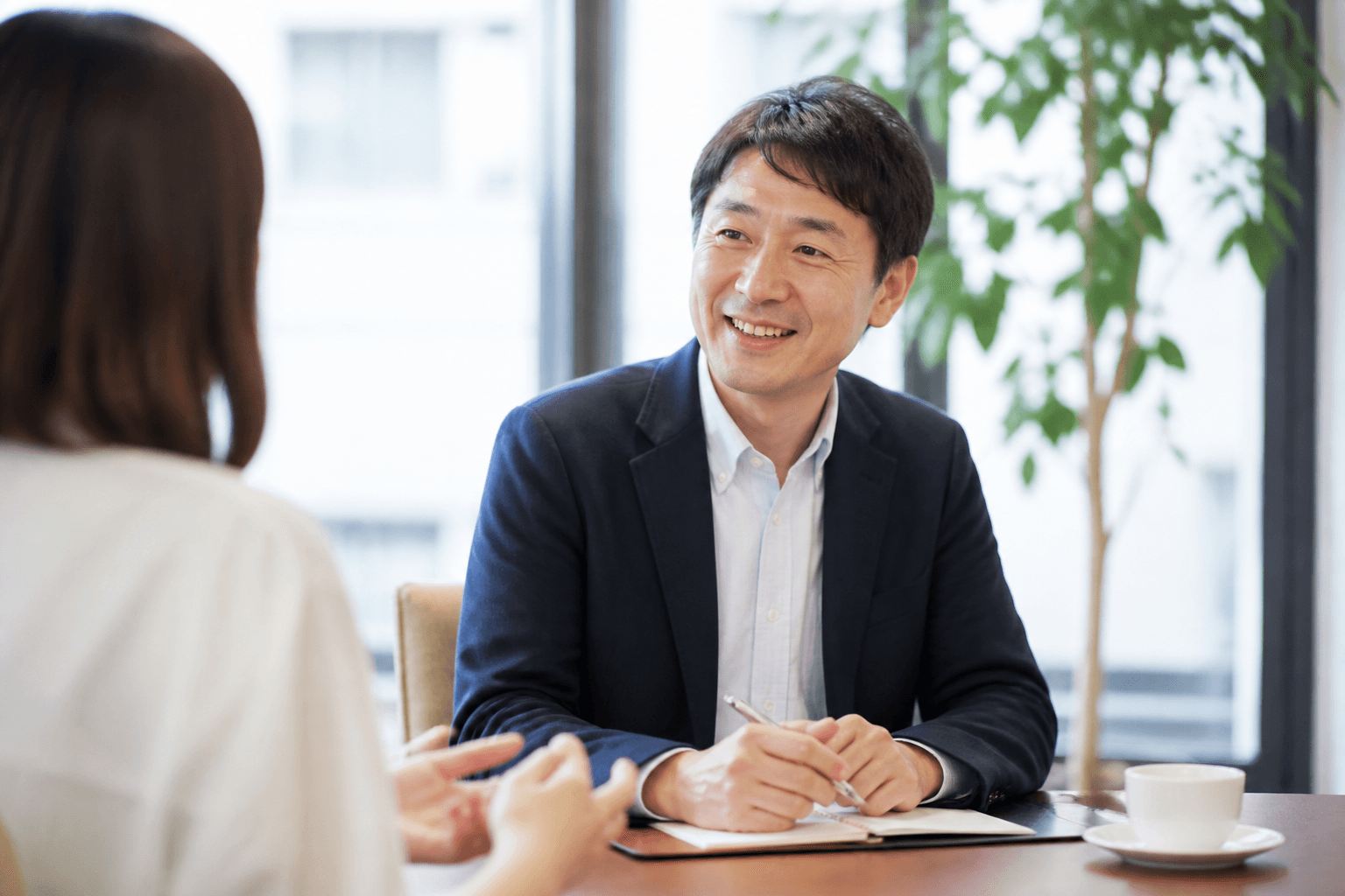 編集長・酒井氏がお客様と和やかな雰囲気でインタビューしている様子の写真]