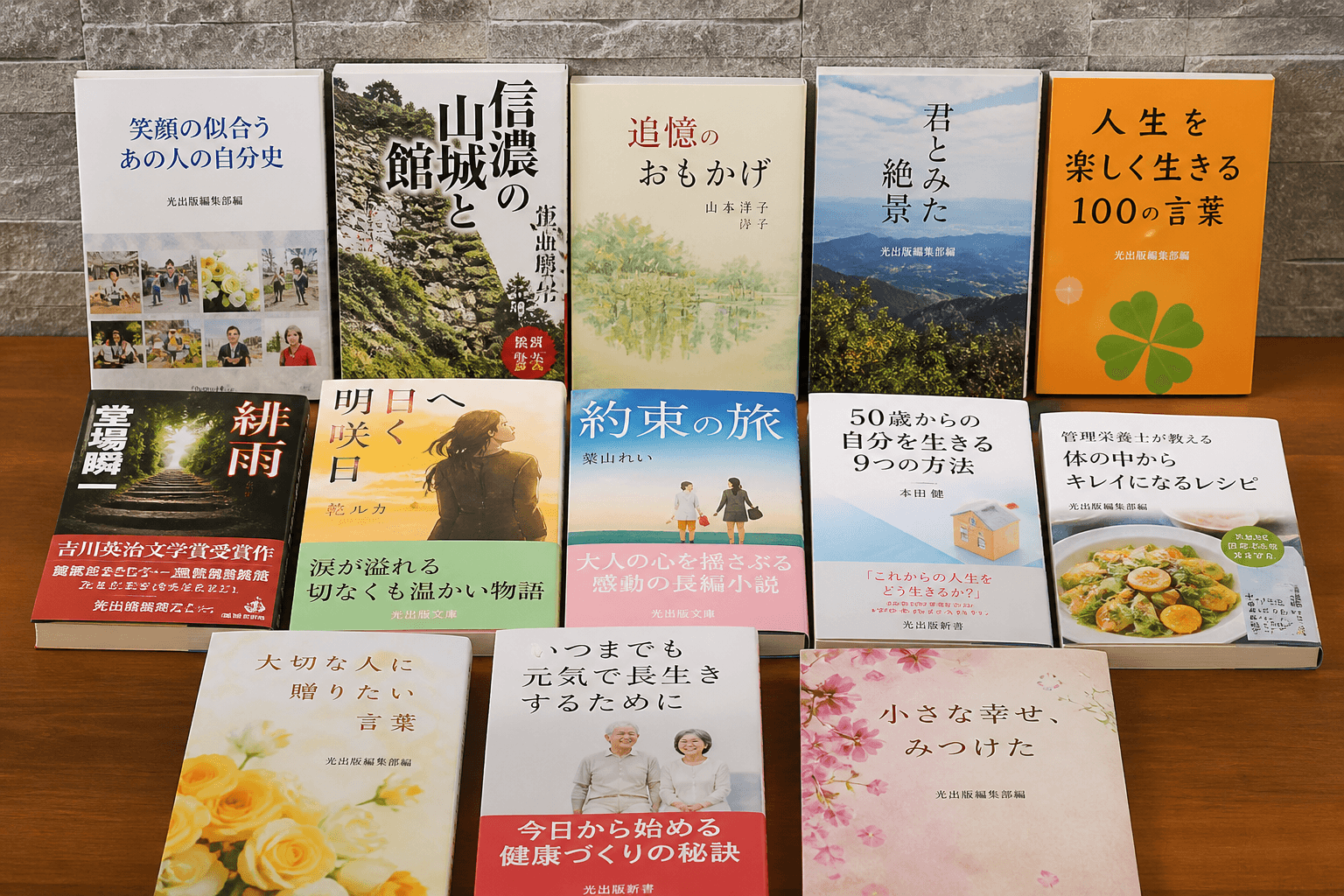 光出版で制作された様々なジャンルの本（自分史、小説、実用書など）が美しく並べられている写真]