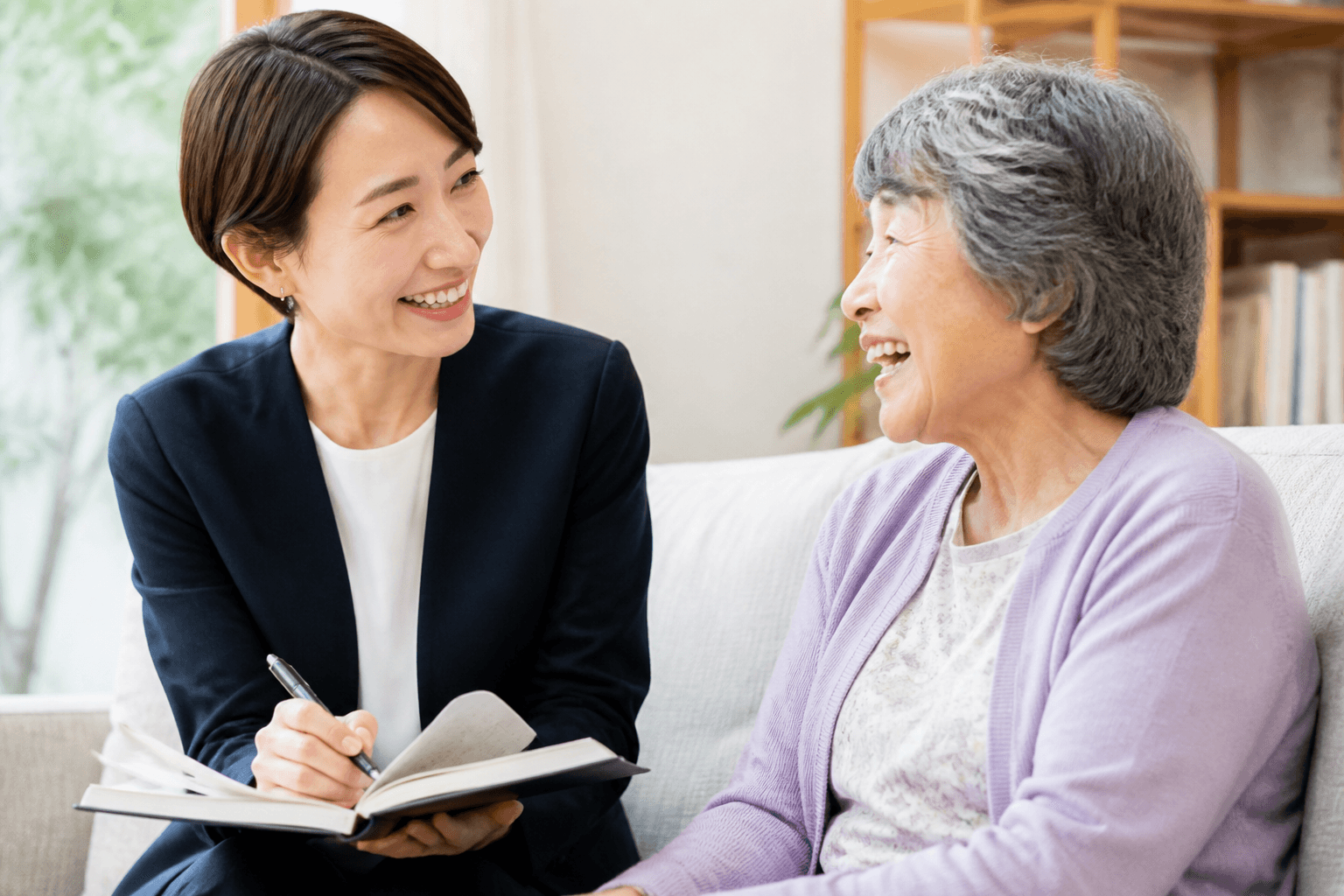 編集者が高齢のお客様に寄り添い、和やかな雰囲気でインタビューしている様子の写真]